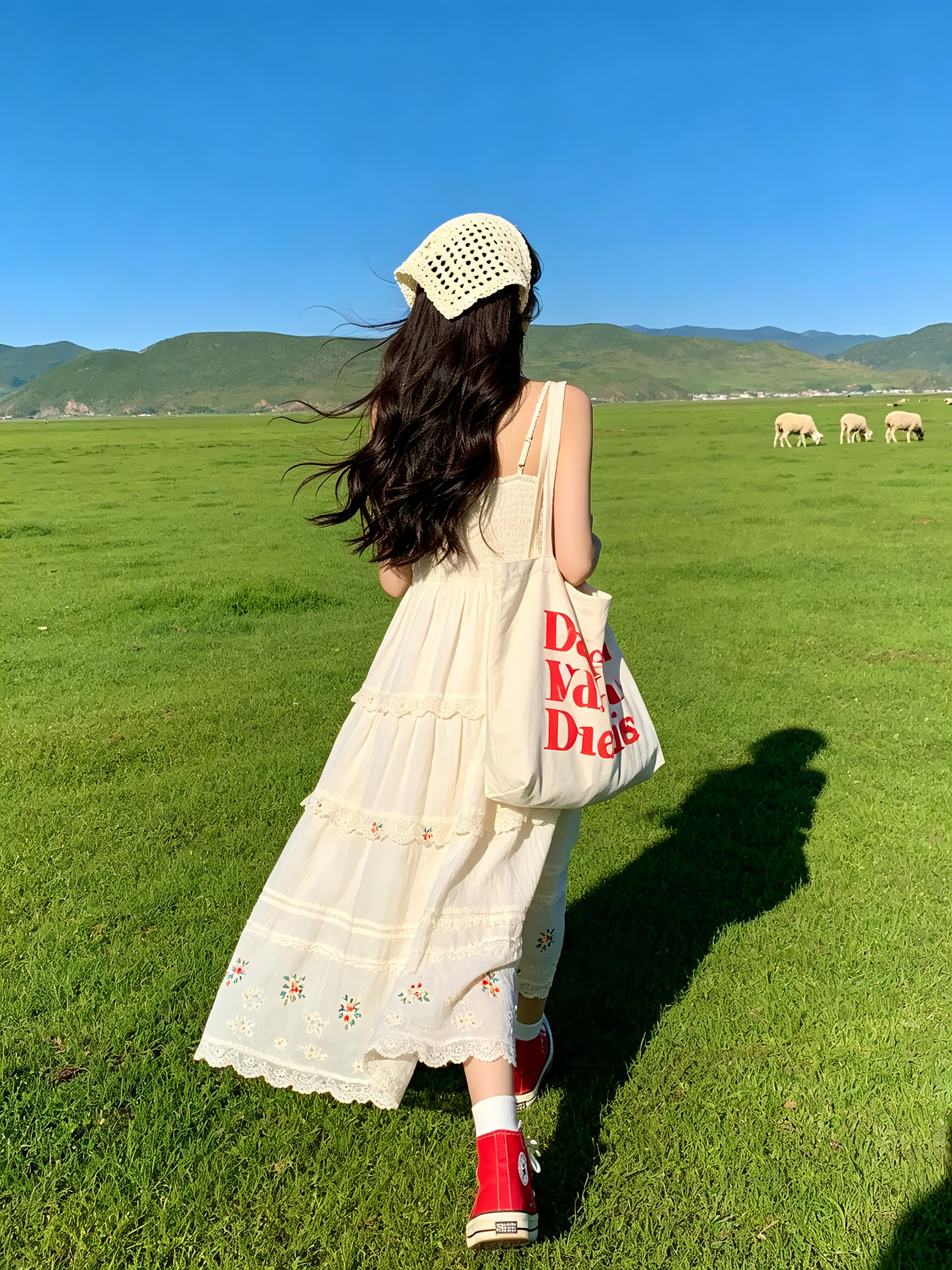 人物：背身长发少女，头戴米白镂空针织头巾，米白刺绣花边吊带长裙，红色帆布鞋，身旁放红色印字帆布包；走在在草坪上，发丝随风飘动。 场景：大片平整翠绿草原，远处连绵青山，几只绵羊漫步，干净高饱和湛蓝晴空。 构图：9:16竖… - AI提示词参考图，来自西西提示词