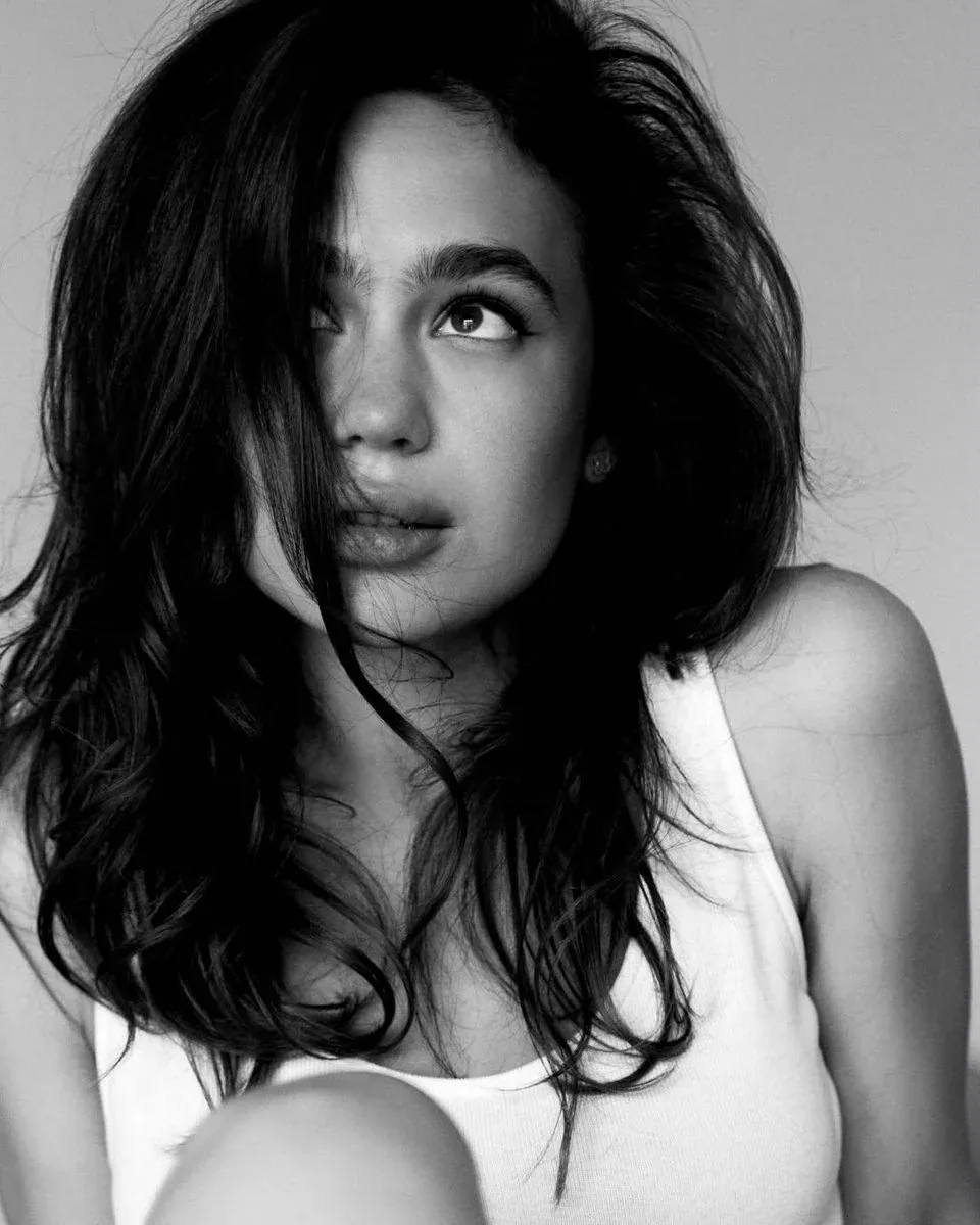Ultra-realistic black-and-white editorial fashion portrait of a young woman with long, voluminous dark hair, … - AI提示词参考图，来自西西提示词
