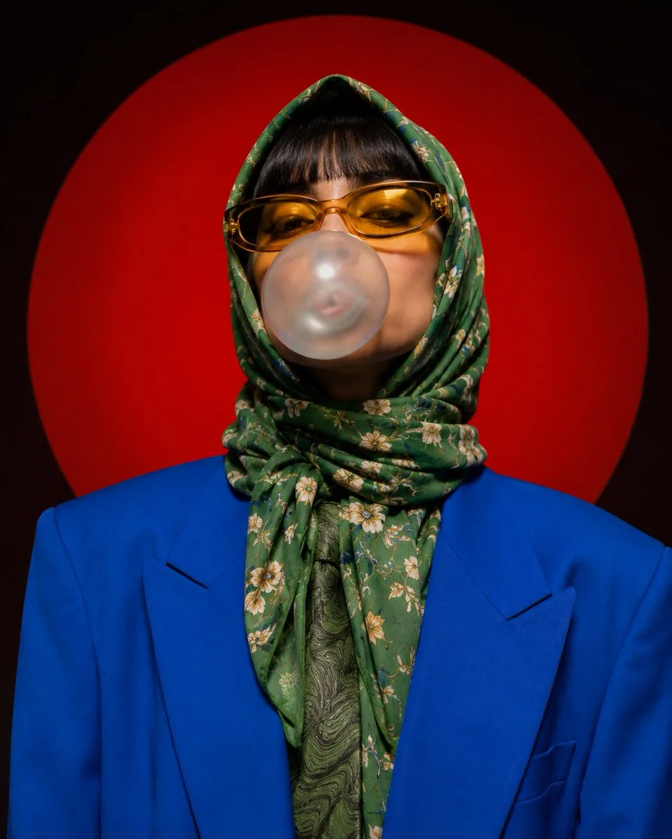 A stylized portrait photograph against a large red circular background. The subject wears a bright blue blaze… - AI提示词参考图，来自西西提示词