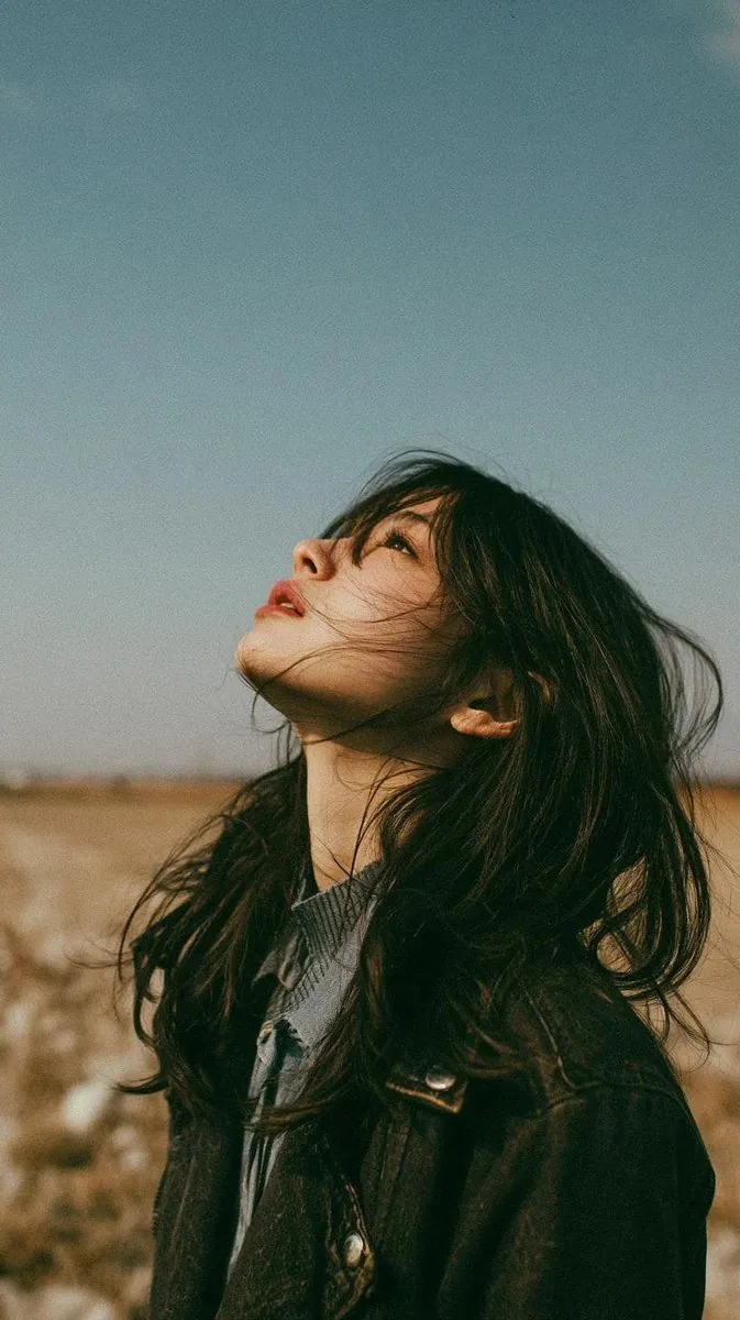 Cinematic minimalist portrait of a beautiful young East Asian woman standing alone in an open wildflower mead… - AI提示词参考图，来自西西提示词