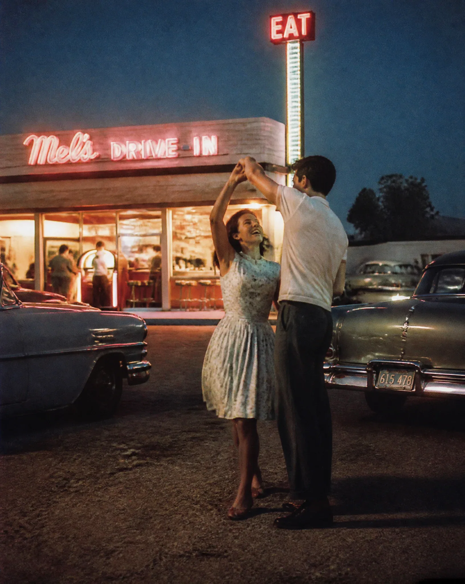 1956 roadside diner at blue hour, a young couple spontaneously slow dancing beside a glowing jukebox heard fr… - AI提示词参考图，来自西西提示词