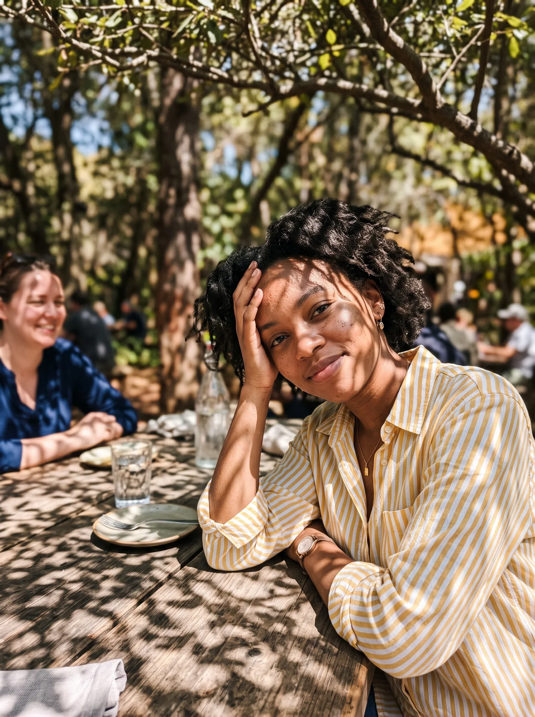 A young woman in a yellow-and-white striped button-up shirt leans toward the camera at an outdoor table, rest… - AI prompt reference from CC Prompt Galaxy