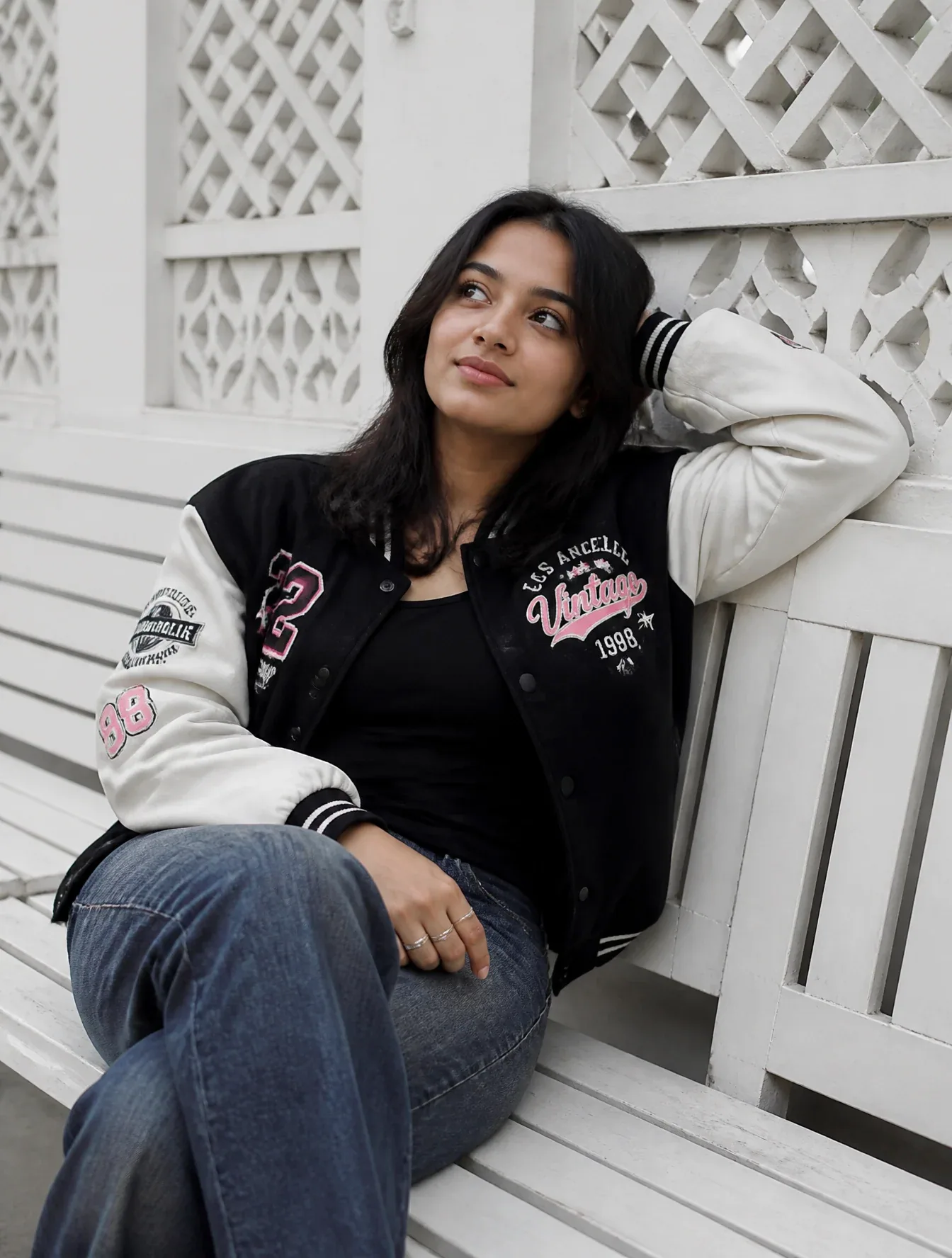 A young woman is sitting casually on a white wooden bench, positioned slightly off-center, with her legs cros… - AI prompt reference from CC Prompt Galaxy