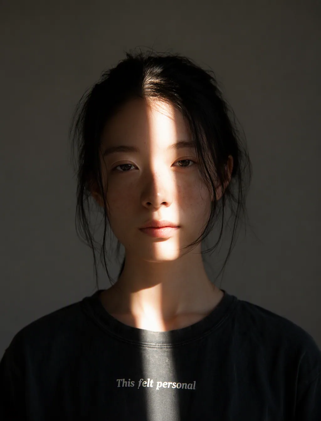 a starkly lit portrait of an asian woman with black hair gathered back, facing the camera against a flat, neu… - AI提示词参考图,来自西西提示词